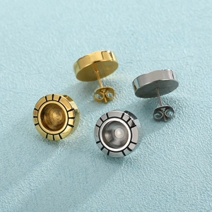 Boucles d'oreilles rondes en acier titane doré et argenté sur un fond bleu texturé