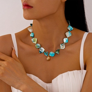 Collana bohémien con ciondolo a conchiglia dorata e perle turchesi su una modella