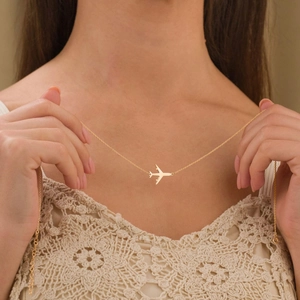 Gros plan d'un collier pendentif avion plaqué or 18 carats porté par un mannequin