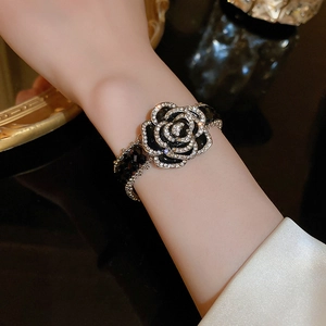 Detail of camellia bracelet with black enamel petals and crystals on model's wrist