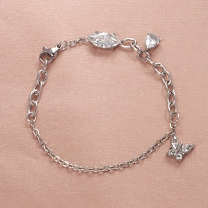 Elegant silver bracelet with zirconia heart, pear-cut stone and butterfly charm on satin