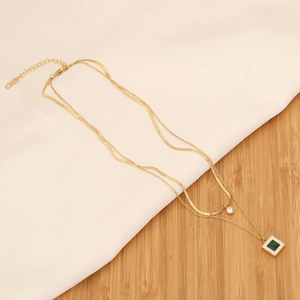 Double layer gold necklace featuring emerald pendant and zircon on silk background