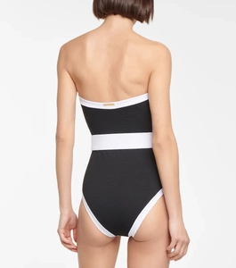 Detailed back view of black and white contrast swimsuit with golden brand metal plate