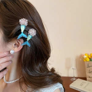 Detail of teal gradient mermaid tail hair clips with pink pearls on model's hair