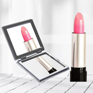 Portable folding square makeup mirror with clear reflection and pink lipstick on grid desk