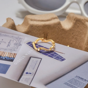 Détail macro d'une bague vague en acier inoxydable doré 18K avec des diamants blancs