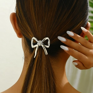 Close-up of a glossy silver metal bow hair tie worn on a ponytail with a mirror finish
