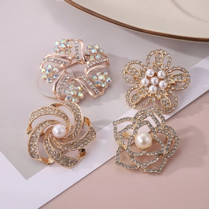 Détail de quatre broches florales avec placage à l'or, cristaux et perles blanches