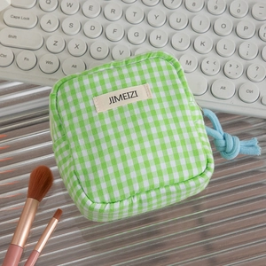 Detail of green gingham storage pouch with blue rope zipper pull and logo patch