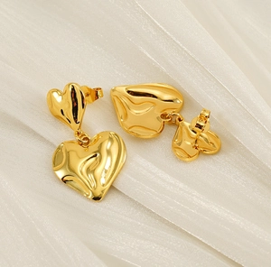 Détail de boucles d'oreilles cœur or 18K à texture lave sur fond de soie blanche