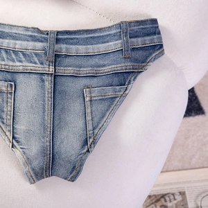 Dettaglio ravvicinato di micro pantaloncini in denim blu con cuciture gialle a contrasto