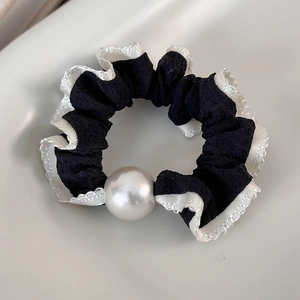 Detailed view of polka dot scrunchie with lace edge and large pearl center embellishment