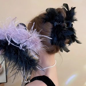 Close-up of large hair claw clip with fluffy ostrich feathers in black and purple