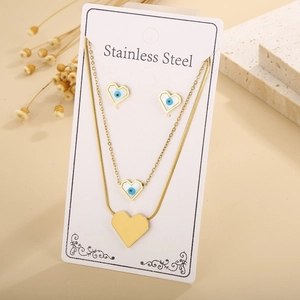 Detail of gold stainless steel heart and evil eye necklace set displayed on a card