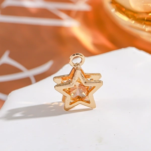 Macro shot of gold star charm with orange zircon on white stone surface for DIY jewelry