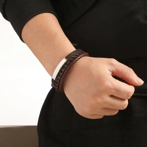 Detail of brown multi-layer braided leather bracelet with metal clasp on male wrist