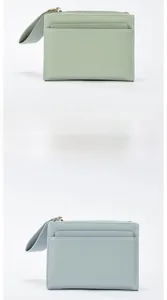 Detail of mint green and blue cross-grain leather wallets with metal zipper and strap