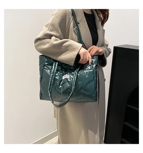 Deep green quilted tote bag shown on a shoulder in a professional studio setting