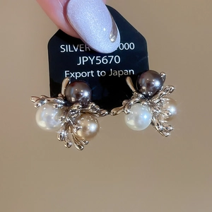 Detail view of French vintage floral pearl earrings with silver posts on a display card