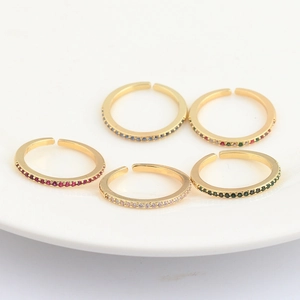Detailed view of five adjustable gold rings with colorful micro-set cubic zirconia stones