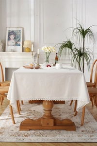 Detailed close-up of white cotton tablecloth featuring delicate lace edges on a wooden table