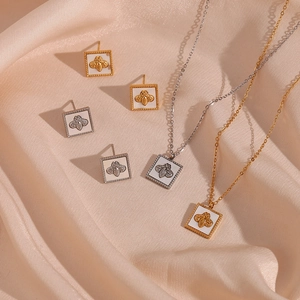 Detail of bee necklace and earrings set with shell inlay on golden silk fabric