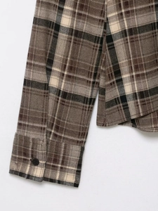 Close-up of the plaid shirt cuff with single black button and thick flannel texture