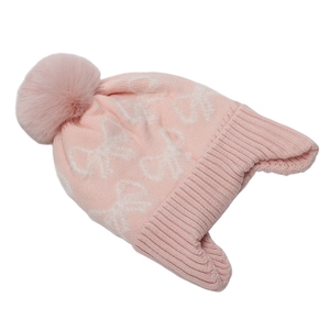 Dettaglio del cappello in maglia rosa con motivo a fiocco bianco e pompon di pelliccia