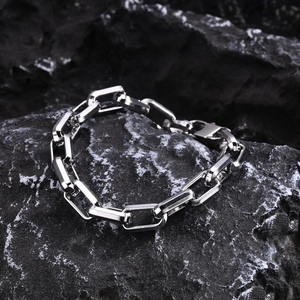 Detail of silver stainless steel geometric curb chain bracelet on a dark rock surface