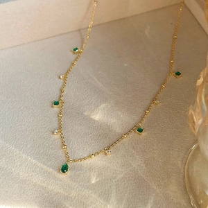 Detail of vintage gold necklace with emerald drop pendants and sparkling cubic zirconia