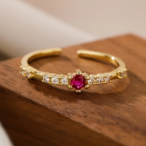 Vintage 18K gold plated ring with a central red zircon and white diamonds on wood stand