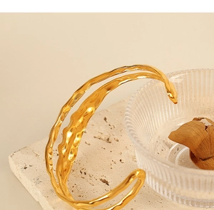 Detail of gold-plated titanium steel bracelet featuring an irregular textured wave design