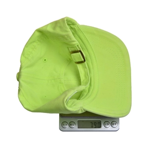Macro shot showing fluorescent green cotton baseball cap weighing 79.0g on a digital scale