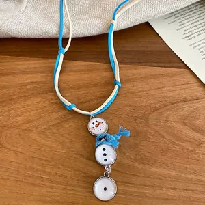 Charmant collier gland bonhomme de neige avec écharpe bleue sur surface en bois