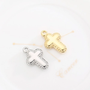 Polished gold and silver cross pendants with woven texture edge on a ceramic plate