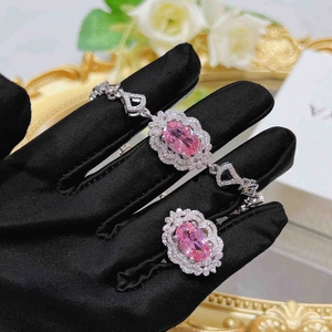 Detailed macro view of pink oval crystal jewelry set with silver floral halo bracelet and ring