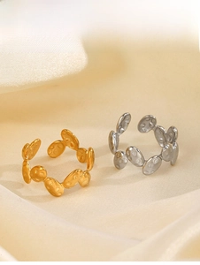 Detail of irregular textured oval rings in gold and silver finish on silk fabric
