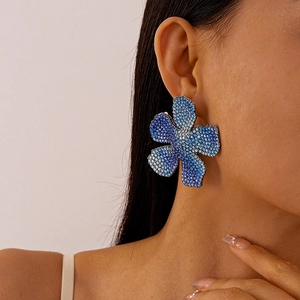 Detail of oversized blue gradient floral earrings with sparkling inlaid rhinestones on model
