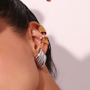 Detailed view of layered wing stud earrings with gold and silver ear cuff accents