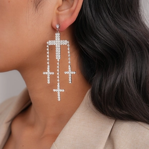 Close-up of sparkling rhinestone cross dangle earrings worn on model for a glam look