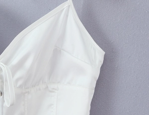 Detalle del top de satén blanco con cuello halter mostrando costuras y tirantes finos