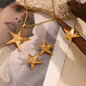 Golden starfish jewelry set with necklace, earrings and ring on a natural rock background