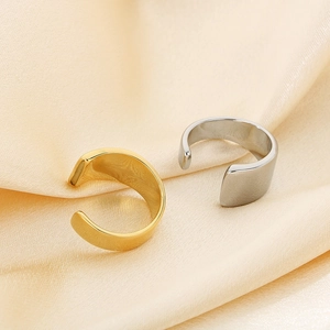 Close-up of polished gold and silver wide open rings on soft beige satin fabric