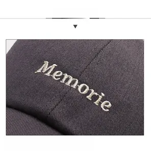 Macro view of white Memorie letter embroidery on dark grey cotton baseball cap