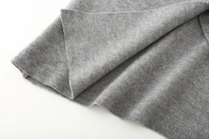 Macro del tessuto in maglia grigia che mostra la trama dettagliata e la fibra del cappotto