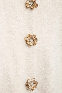 Détail des boutons floraux avec perles sur un cardigan en maille crème élégant