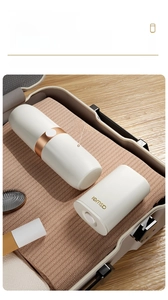 Boîte à savon et gobelet de voyage rangés dans une valise sur une serviette douce