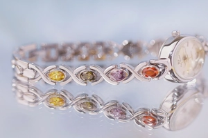Macro view of silver watch band set with colorful gemstones and Bee Sister logo