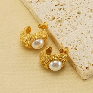 Détail macro de boucles d'oreilles en C plaquées or 18k avec texture tissée et perle blanche