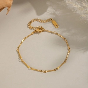 Macro view of gold-plated stainless steel bone-link chain with S.STEEL engraving detail